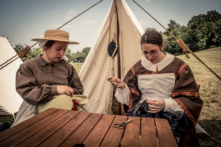 Vivandiere engaged in tailoring activities mend civilian clothes at the camp., 19th Century: American Civil War, Borzano di Albinea, Reggio Emilia, Italy (photo)