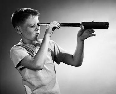 Boy looking through a hand-held telescope