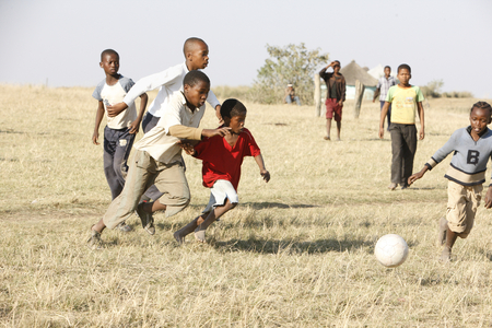 Group of African Children playing soccer / football in the Townships, Cape Town, South Africa (photo)