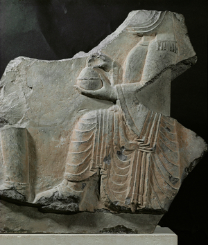 Sitting Priest holding a vase with offerings …