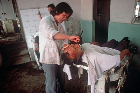 woman barber shaving man in barber shop, Shaoxing, China (photo)