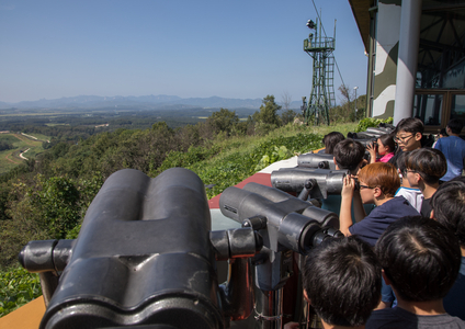 Children using binoculars in front of freedom and railway bridge over Imjin river between north and south Korea, North Hwanghae Province, Panmunjom, 2016 (photography)