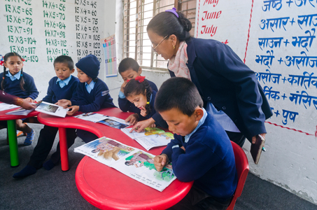 Primary school children and teacher reading picture books together in rural Nepali school, 
Lwang Ghalel, Annapurna Conservation Area, Himalayas, Nepal (photo)