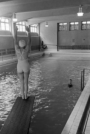 Young woman standing on the diving tower in a swimming pool, Freudenstadt, Germany 1930s (b/w photo)