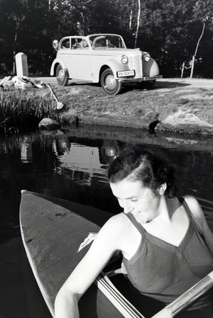 Young woman paddling in a boat on a lake near the river, Germany 1930s (b/w photo)