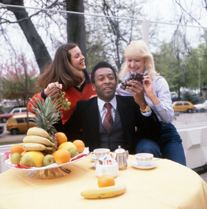 The football legend Pele is having breakfast together with two young women, Germany circa 1970s