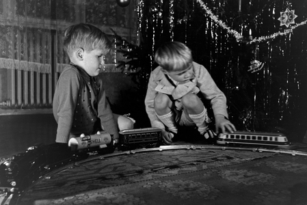 Two boys playing with the new model train under the christmas tree, Germany 1930s (b/w photo)