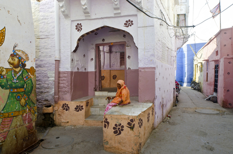 Old Indian lady with stick resting in entrance to painted old townhouse,
The Old City, Jodhpur, Rajasthan, India (photo)