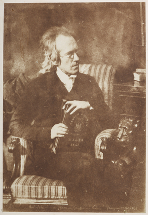 Dr Julius Wood. Three-quarter length seated portrait of the Rev. Dr. John Julius Wood (1800-1877), in half-profile facing right and holding a book in his lap to display the title: 'Scotch Church Malta 1843'..