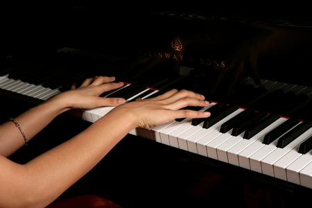 Young female playing a concert grand piano