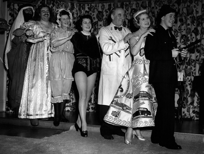 Jan. 01, 1954 - The Dockers attend New Year Ball introducing the” Daimler” dress.: Quite a sensation was created at the New Years Eve Fancy Dress Ball at the Poole Harbour Yacht Club by the unique dress worn by Lady Docker. The dress is white slipper satin embossed with diamante and sequins to represent every make of Daimler car