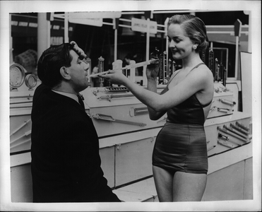 May 05, 1953 - Not good science, but perhaps a good picture. This year's British Industries Fair opened in London in warm weather and a hydrometer at the stand of G.H. Zeal of London was pressed into use strictly in the cause of making a picture. Picture Shows: 20-year-old Maria Sheering, garbed on behalf of the picture, uses a hydrometer on a perspiring visitor to this yearì ¢ ââÃ ¢ s British Industries Fair.