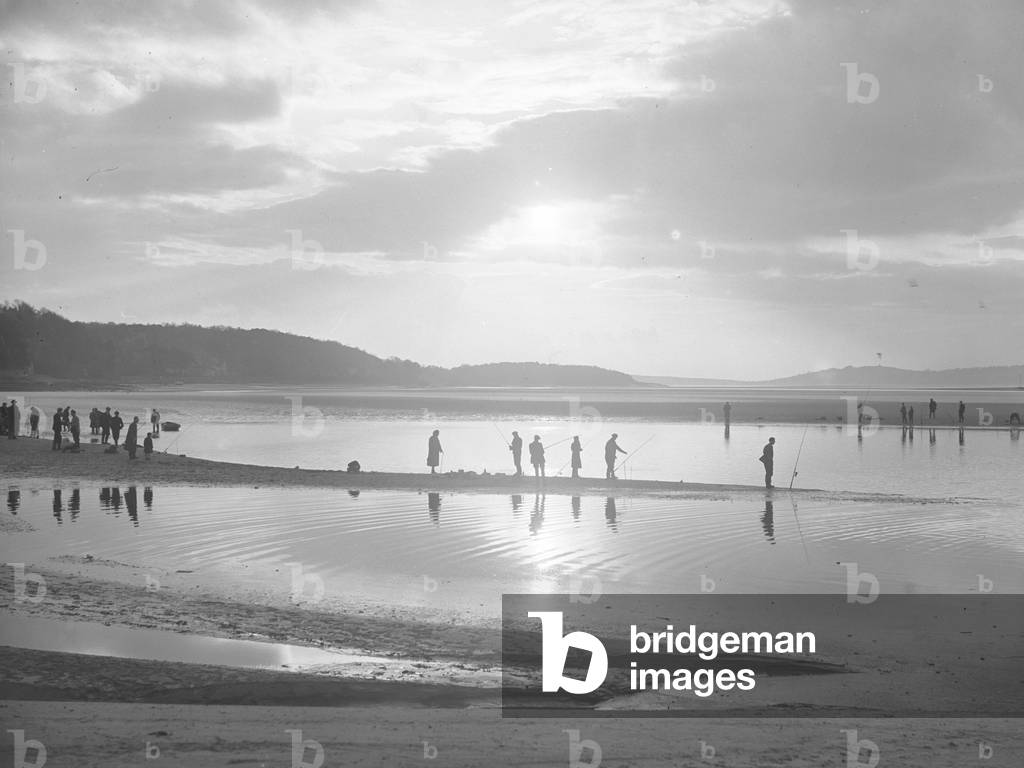 Large group fishing at Arnside standing on spit of land into mudflats, 1930s-60s (b/w photo)