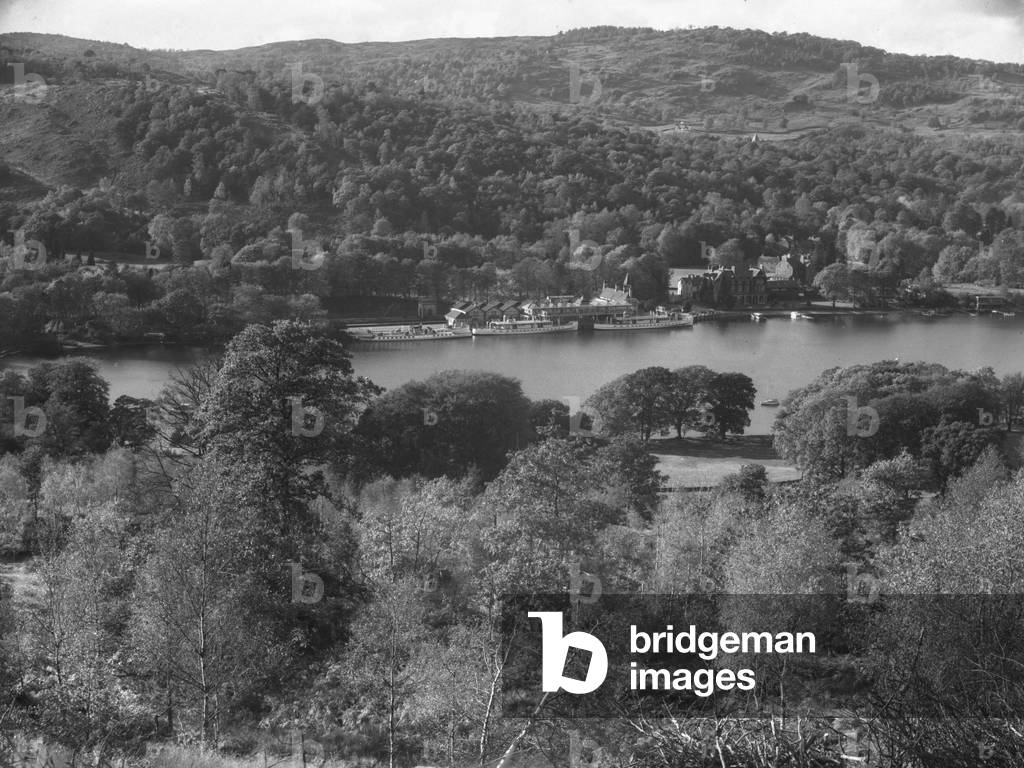 View across a lake with a hotel at the edge and boats moored up alongside, 1930s-60s (b/w photo)