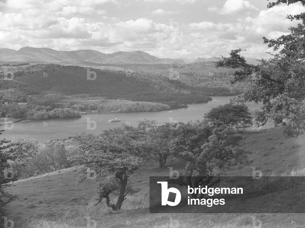A view across a lake with a boat on it, woodland and fells, 1930s-60s (b/w photo)