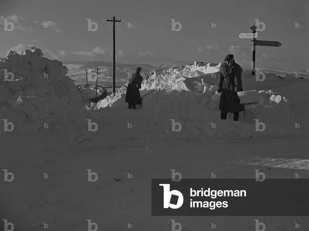 Men clearing road of deep snow near shap with road sign for Shap, Shap Abbey, Haweswater, Rosgill Bampton in background, 1930s-60s (b/w photo)