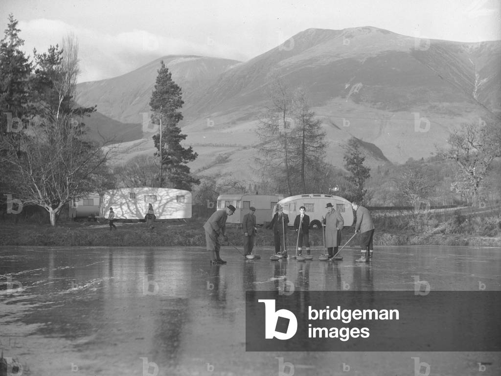 Six curlers on the ice at Keswick with caravans in background, 1930s-60s (b/w photo)
