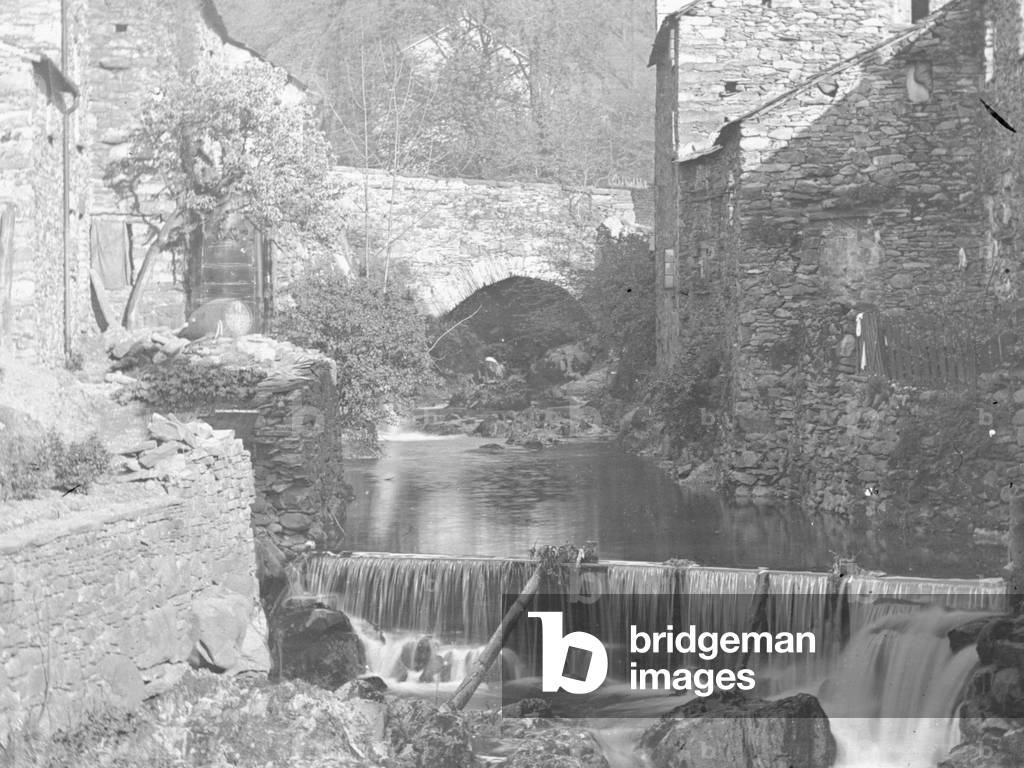 A view of a water course and small waterfall with buildings either side, 1930s-60s (b/w photo)