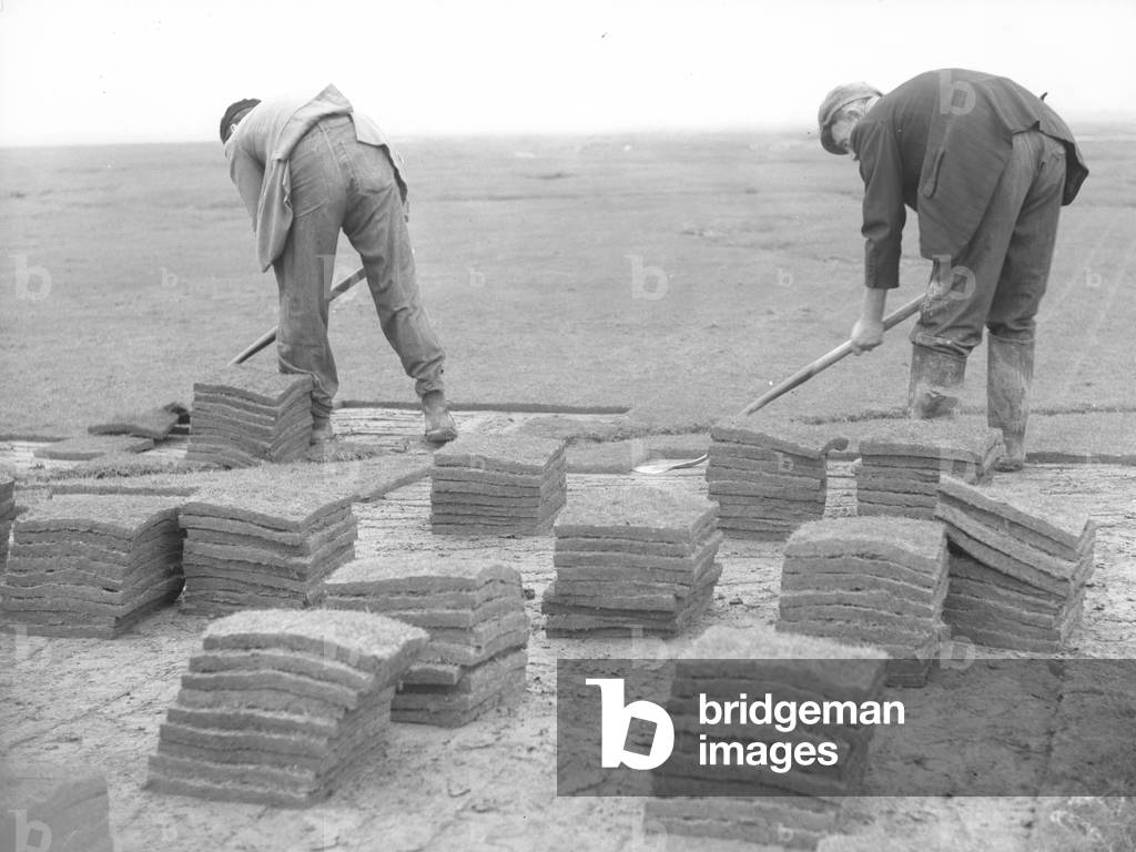 Two men cutting turf or peat and putting it into piles, 1930s-60s (b/w photo)