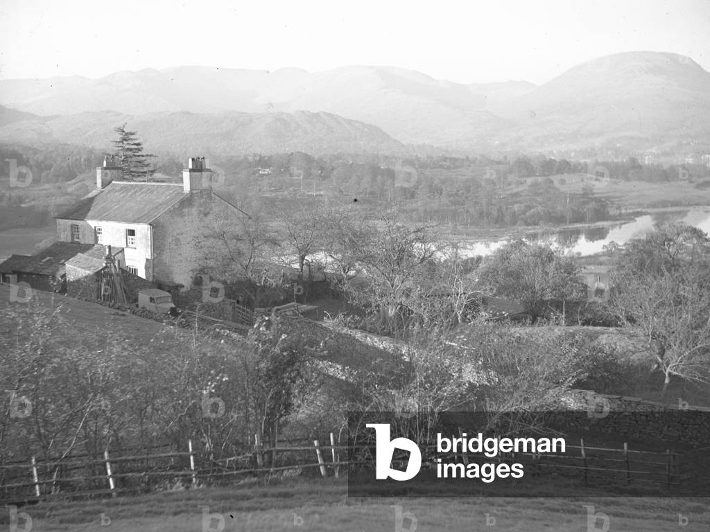 A building (possibly a farm) overlooks a lake, with fells in the background, 1930s-60s (b/w photo)