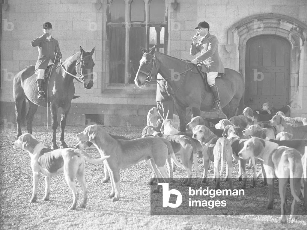 Two mounted horsemen drinking from glasses wth hounds at their feet, 1930s-60s (b/w photo)