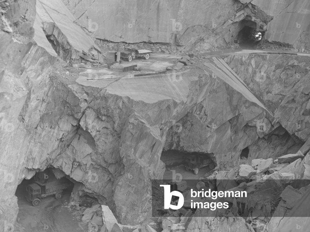 A view into Broughton Moor Quarry showing tunnels in the rock and dumper trucks, 1930s-60s (b/w photo)