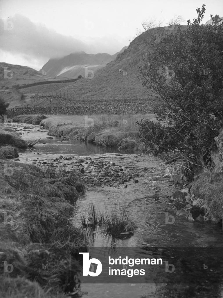 View along mountain stream with fells in background, 1930s-60s (b/w photo)