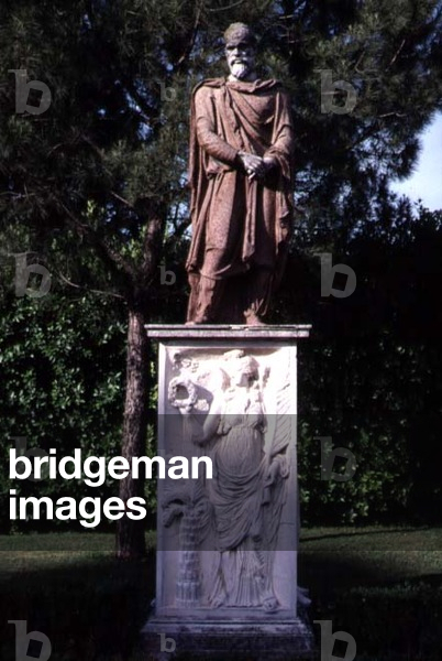 View of the garden, detail of a travertine sculpture of a male figure on a marble relief decorated with a relief of a female goddess (photo)