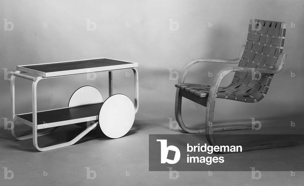(LtoR) Tea Trolley, model No.98, manufactured by Aztek, 1936, and a Cantilevered Armchair '406', 1933, designed by Alvar Aalto (1898-1976) (b/w photo) (wood and leather)