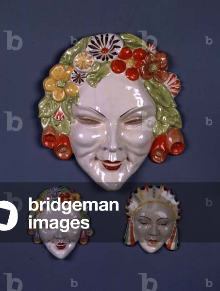 (LtoR) A large and a small 'Flora' wall mask and another decorated with a head-dress, by Clarice Cliff (1899-1972) (ceramic)