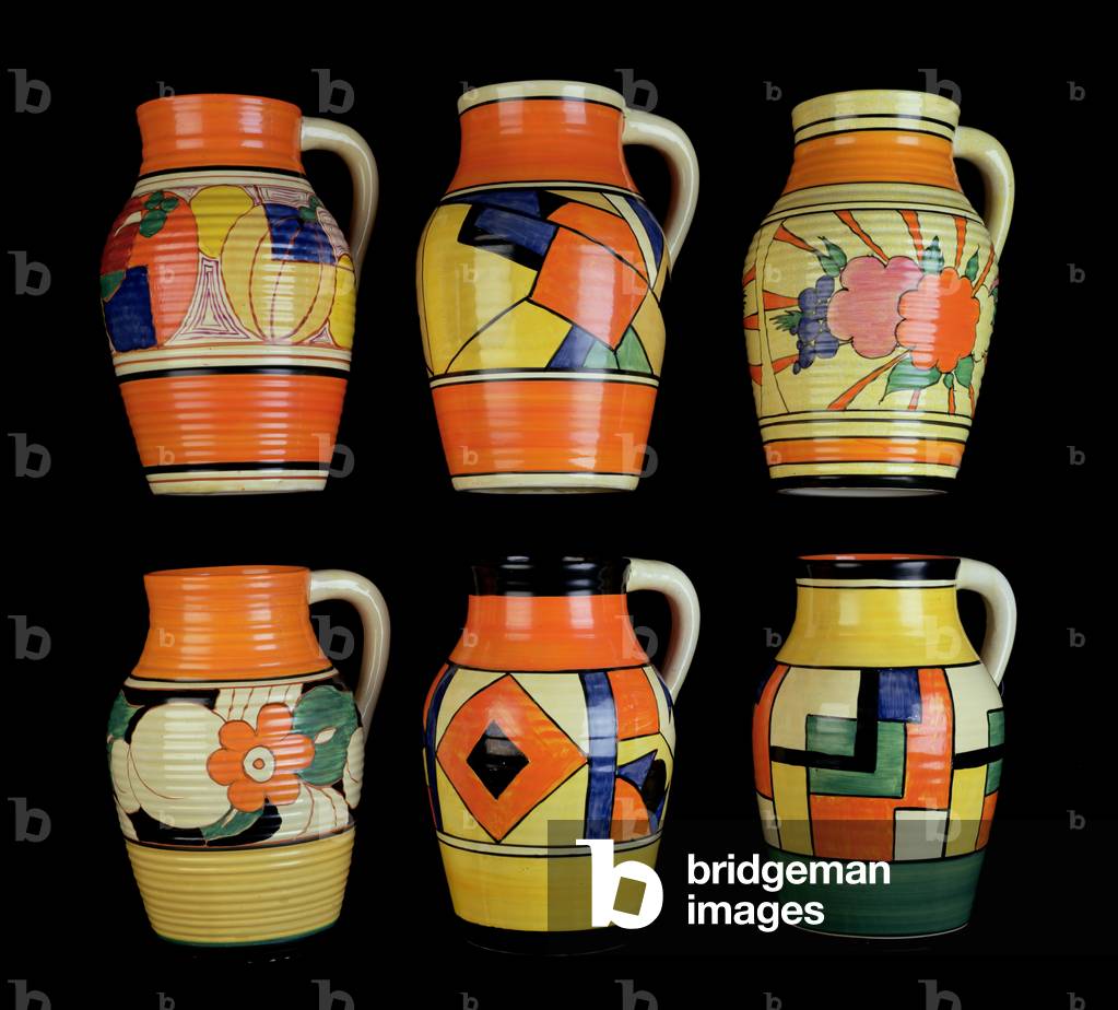 (LtoR) A 'Melon' pattern single handled Lotus jug, a 'Cubist' pattern single handled Lotus jug, a 'Cafe-au-lait Fruitburst' pattern single handled Lotus jug, a 'Floreat' pattern single-handled Lotus jug, a 'Diamonds' pattern single handled Lotus jug and a 'Mondrian' pattern single handled Lotus jug by Clarice Cliff (1899-1972) (ceramic)