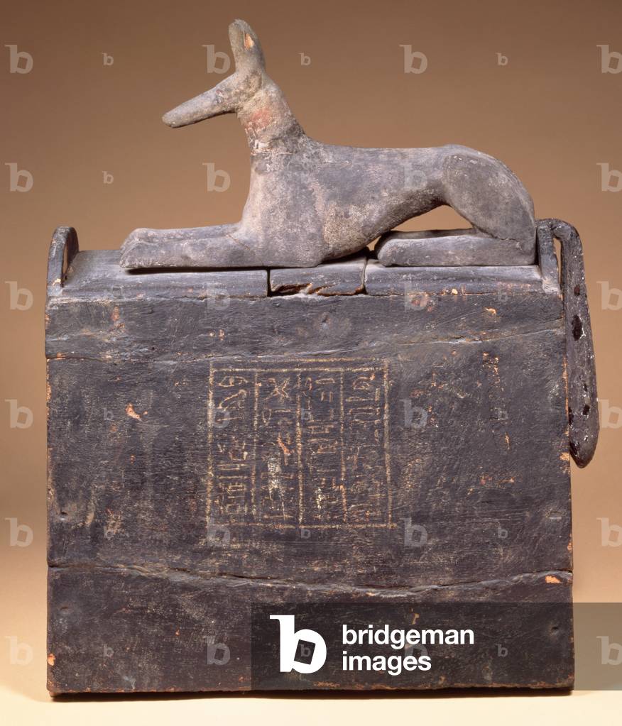 Plyon-shaped shabti-box with an inscription and a statue of Anubis as a jackal (of a later date) on the lid, Egyptian, from Thebes, early 22nd Dynasty, c.900 BC (black-painted wood)