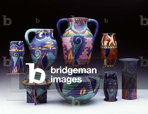 (LtoR) An 'Inspiration' Persian Isnic vase, an 'Inspiration Persian' Isnic single handled Isis jug, an 'Inspiration' Persian design two handled Lotus jug, an early 'Persian' design vase, a 'Inspiration Persian' Isnic rose bowl, an 'Inspiration Persian' Isnic design Jardiniere, and two 'Inspiration' Persian design vases, by Clarice Cliff (1899-1972) (ceramic)