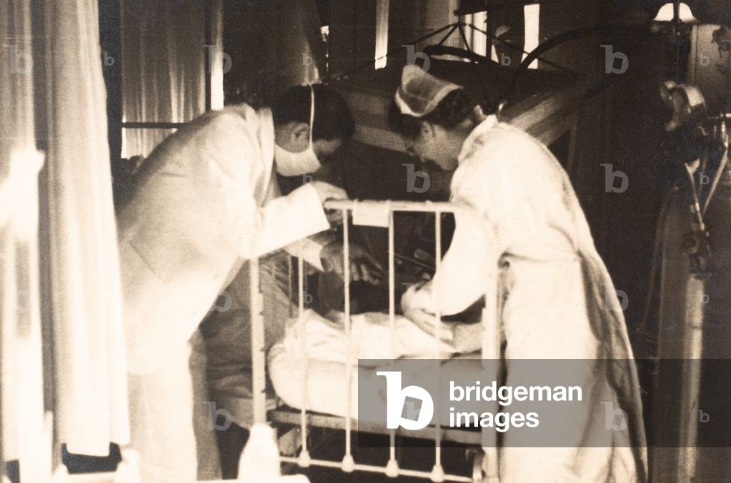 Nurse and Masked Doctor Attend to Patient in Bed, New York City, NY, c.1960-69 (silver gelatin print)