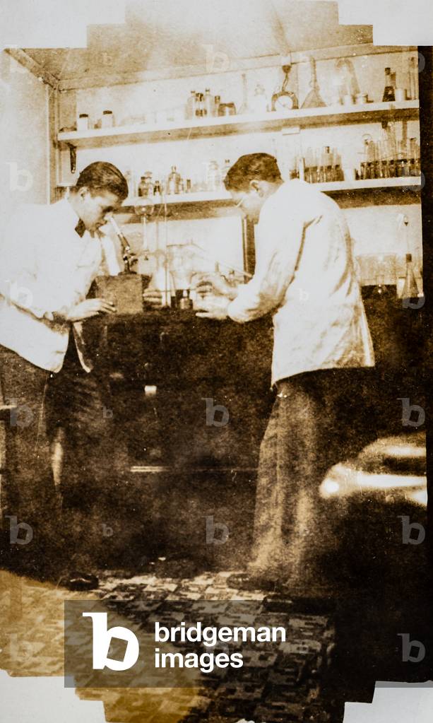 Two Pharmacists at Work, One Looking Through Microscope, c.1925 (silver gelatin print)