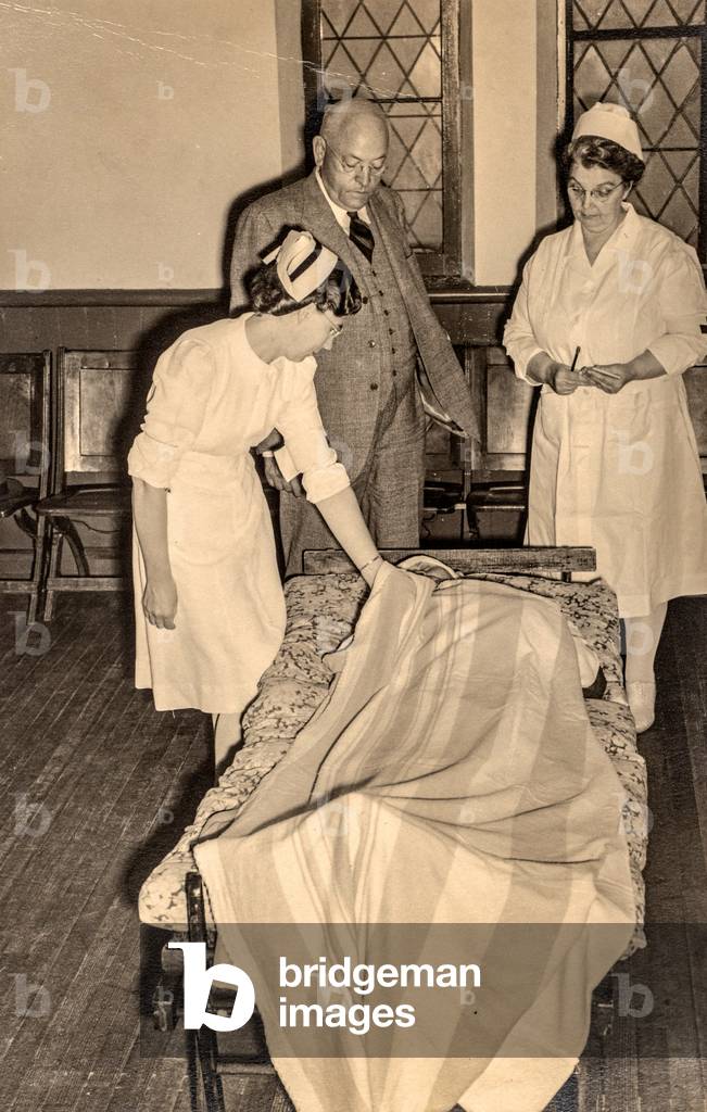 Red Cross Nurses Examine Patient on Cot, c.1940s-1950s (silver gelatin print)