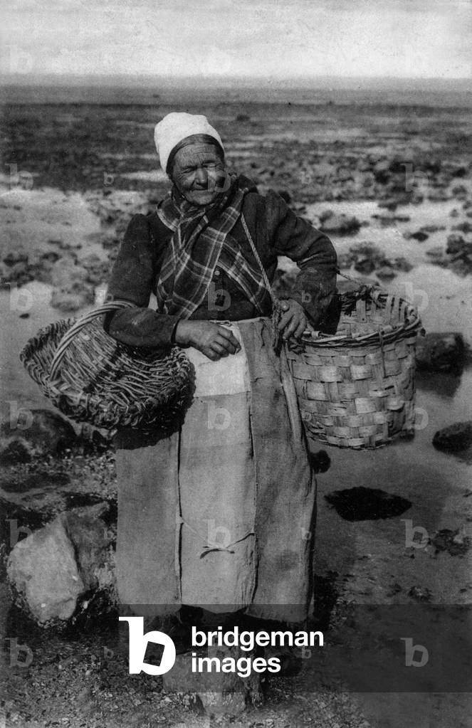 Old woman picking up mussels, France, Brittany, 1970