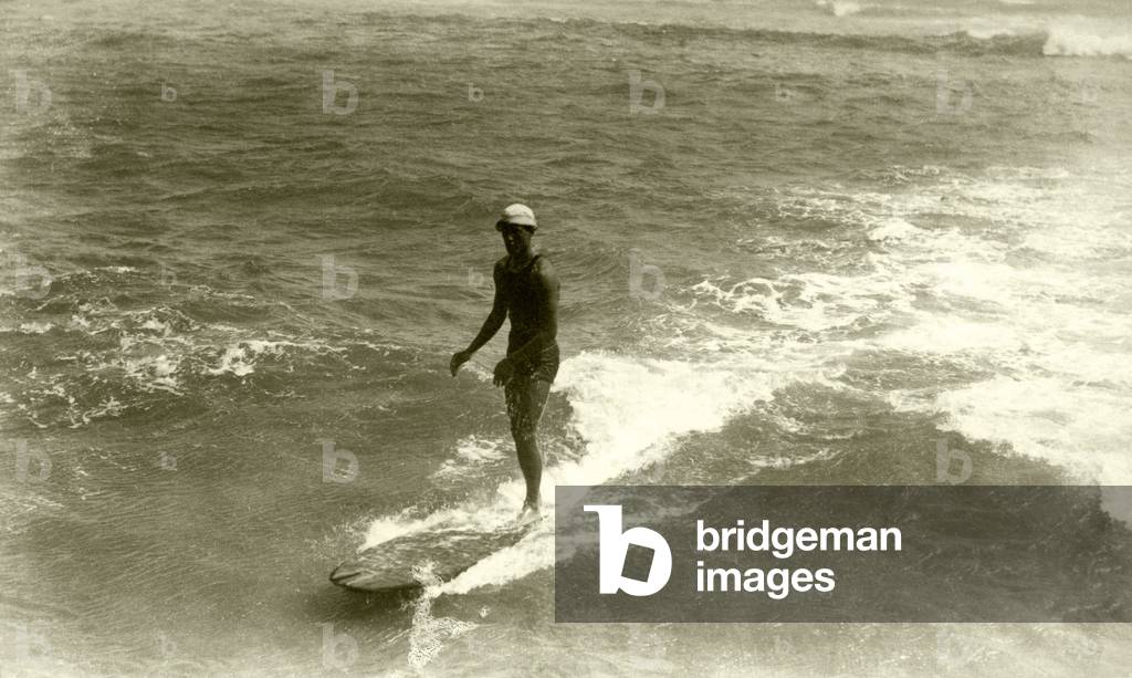 A surfer at Waikiki Beach, c.1920s (b/w photo)