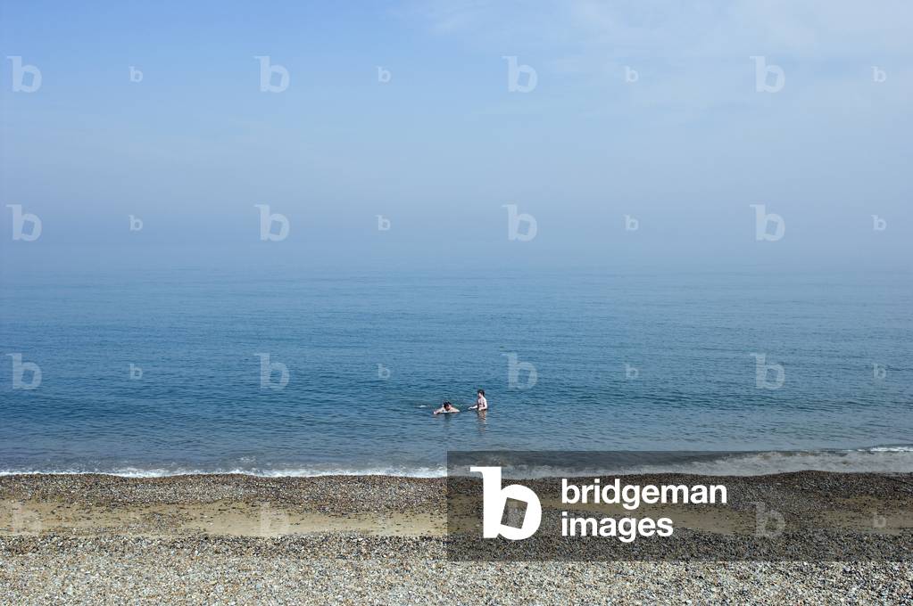 Aldeburgh beach - view over the sea from the beach with people swimming in Suffolk, England