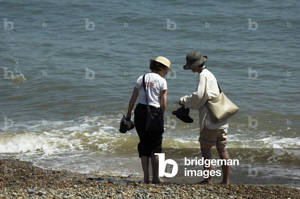 Aldeburgh beach in Suffolk, England with two people paddling in the sea