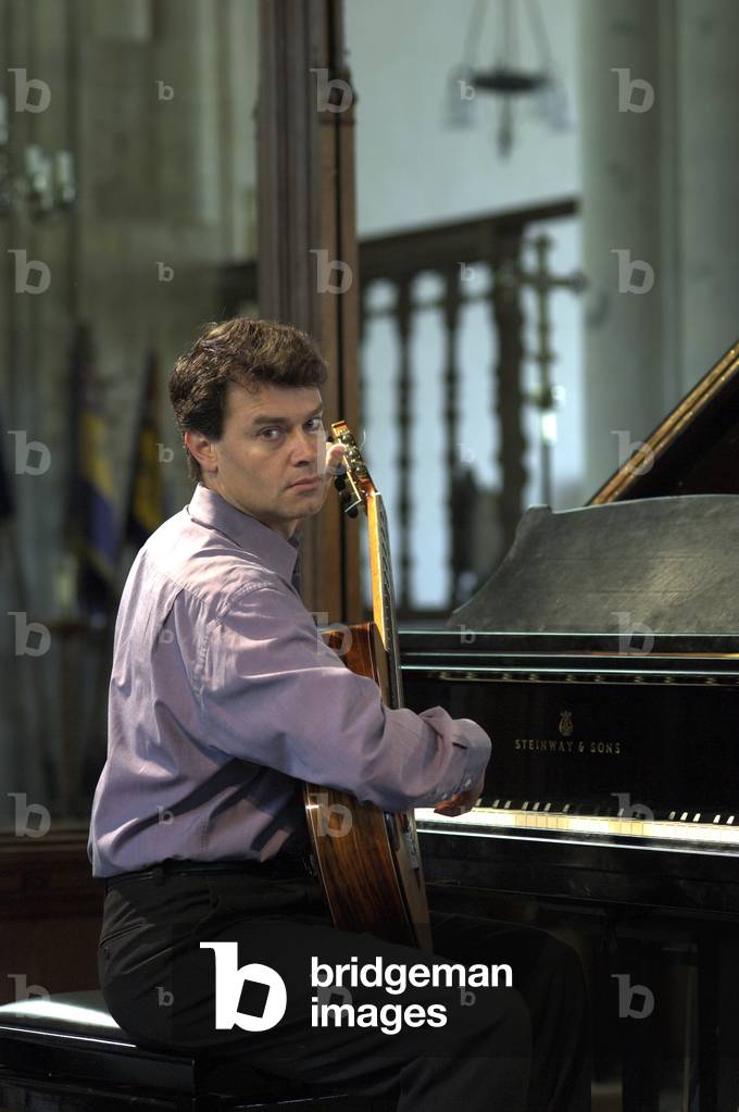 Craig Ogden - portrait of the Australian guitarist playing a classical guitar, sitting in front of a piano in Orford Church at the Aldeburgh Festival, 1 June 2005
