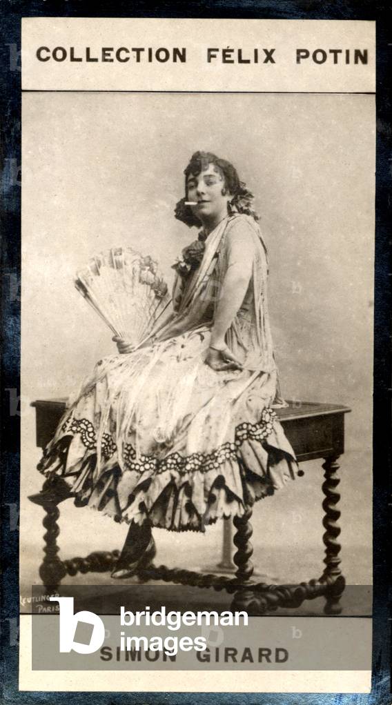 Juliette Simon-Girard with cigarette, sitting on table, holding a fan, in Carmen style