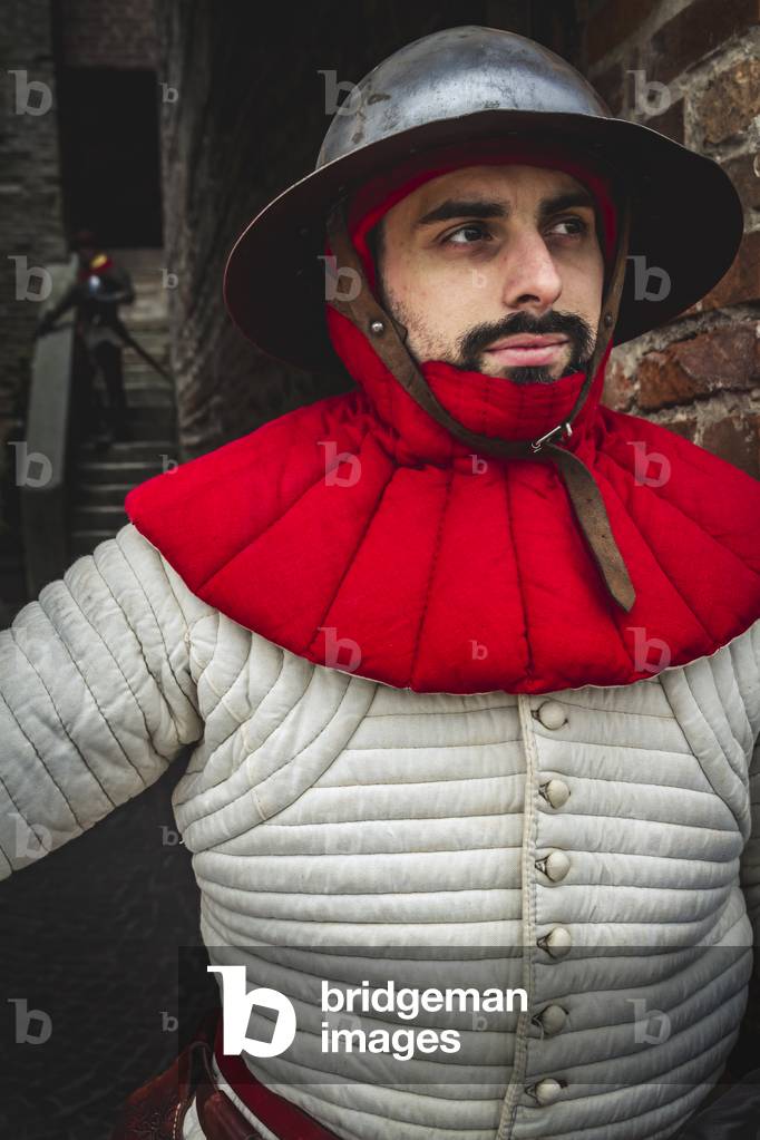 Reconstructive hypothesis of customs and customs, arts and crafts 14th century: Guard at the castle: wearing gambeson and hat of arms, Villafranca di Verona, Veneto, Italy (photo)
