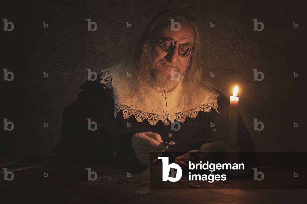 17th century, North Italy: country militia. Reconstructive hypothesis civil and military uses and customs. Cerusico sitting at a table, accounting for the payments received for his performance, Verrua Savoia, Turin, Piedmont, Italy (photo)