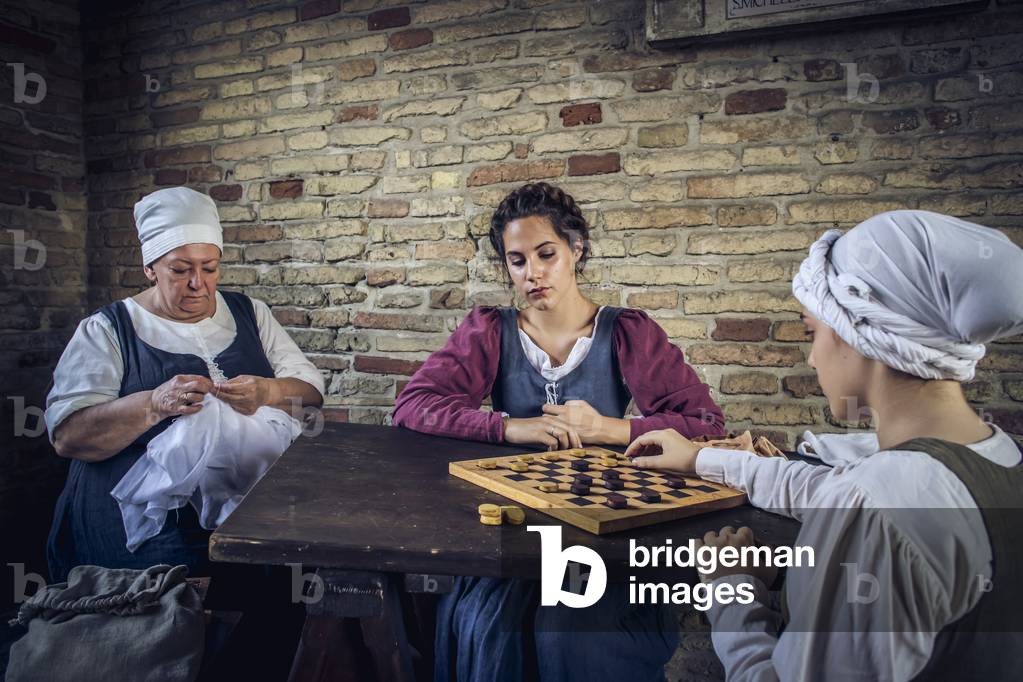 You play checkers and embroidered under a porch to shelter from the summer heat, hypothesis reconstructive uses and customs Middle Ages Italy, Mondaino, Italy (photo)