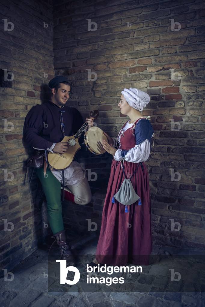 A boy and a girl, improvise a music with string and percussion instruments, Reconstructive hypothesis uses and customs Middle Ages Italy, Mondaino, Italy (photo)