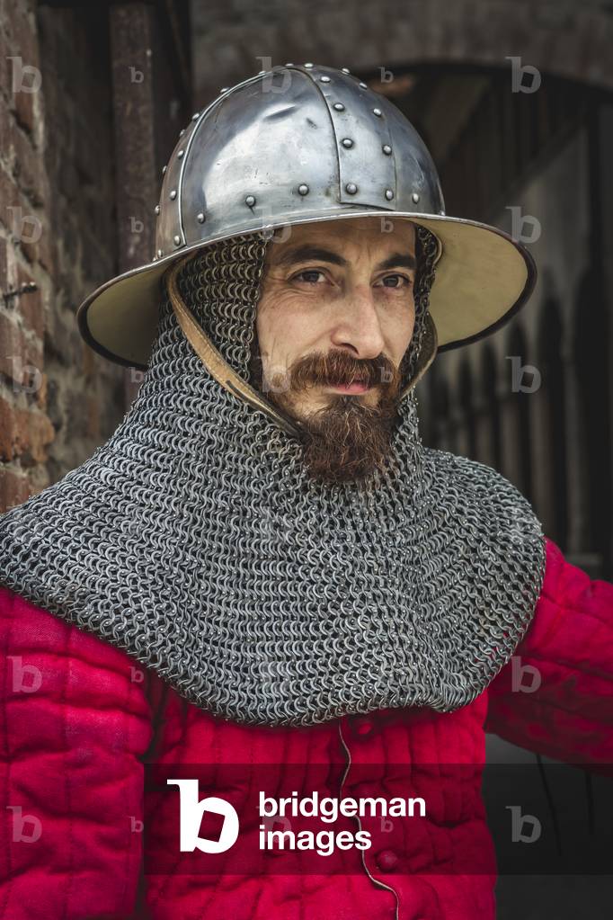 Reconstructive hypothesis of customs and customs, arts and crafts 14th century: Guard at the castle: wearing gambeson and hat of arms, Villafranca di Verona, Veneto, Italy (photo)