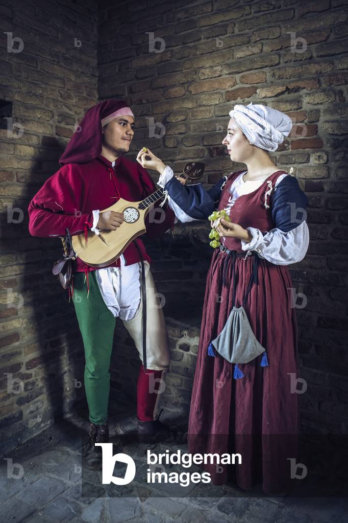 A girl offers a grape grain to the boy who is dedicating a love song to her, Hypothesis reconstructive uses and customs Middle Ages Italy, Mondaino, Italy (photo)