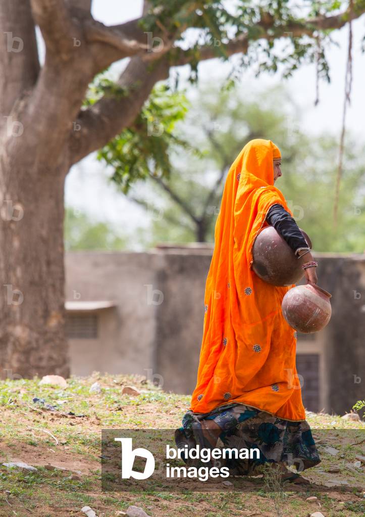 Traditionally dressed woman with water pots, Bishangarh, Jaipur, Rajasthan, India, June 2018 (photo)
