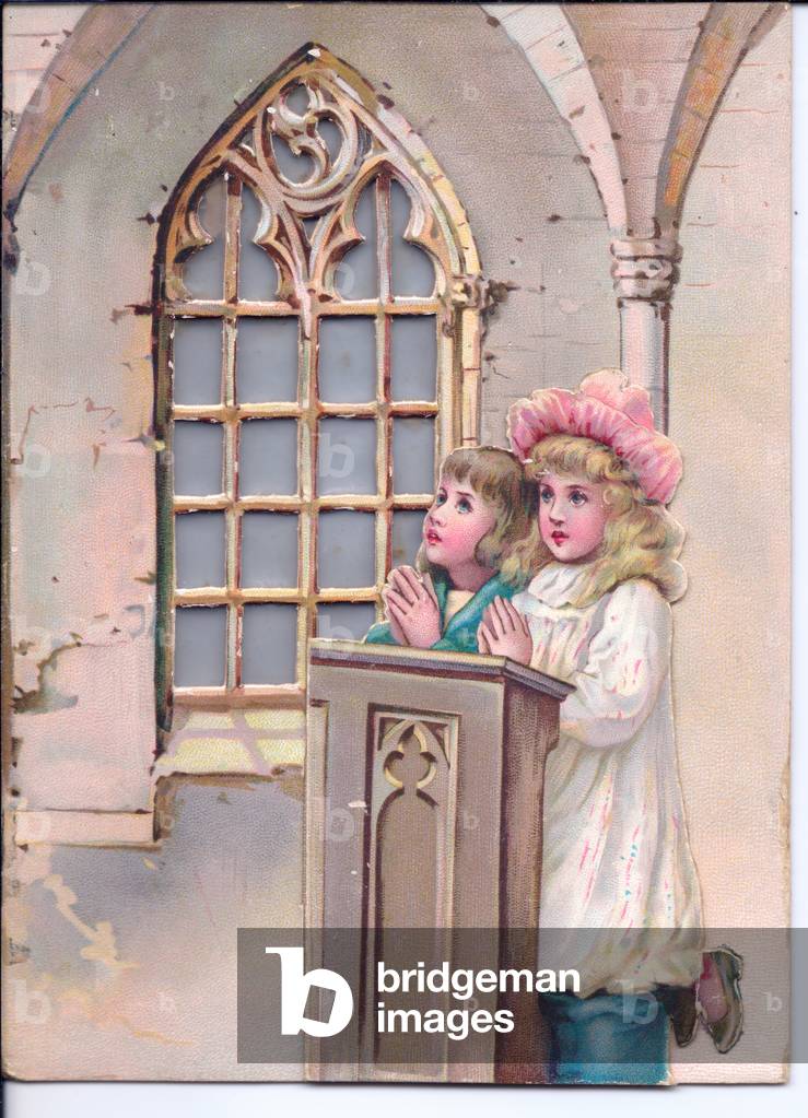 A Victorian hold-to-light Christmas Card of a boy and girl praying in church. Light shines through the gothic window when the card is held to a light source, circa 1880 (coloured lithograph)